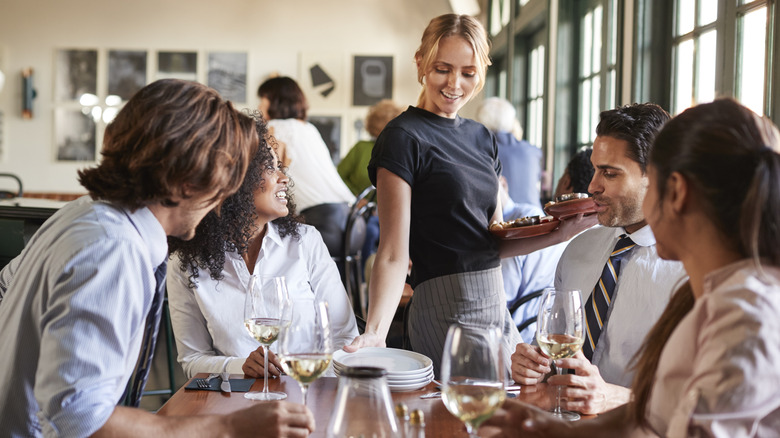 Busy restaurant with waitress serving full table
