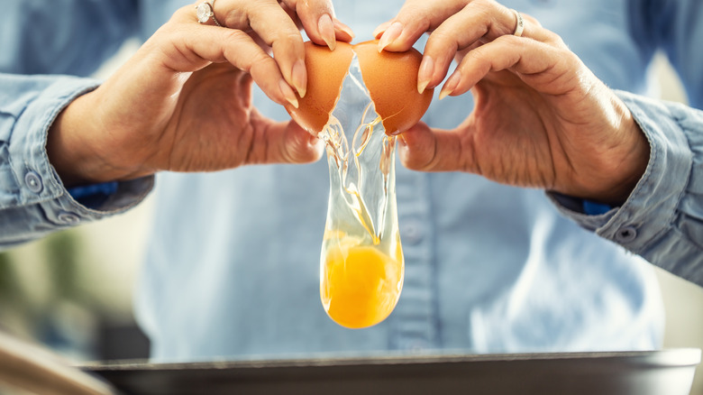 Person cracking egg with two hands