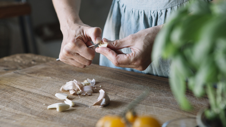 Person peeling garlic on a cutting board