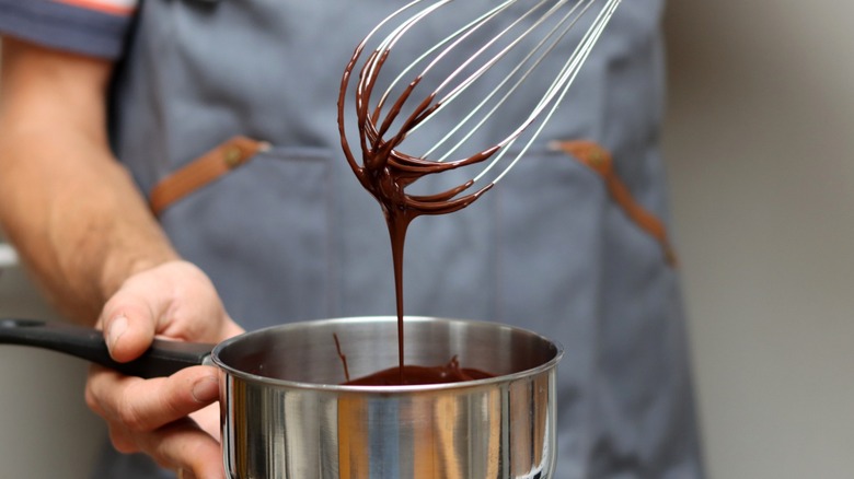 baker checking the consistency of their chocolate ganache