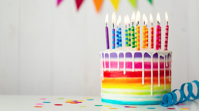 rainbow-colored birthday cake with white drip frosting