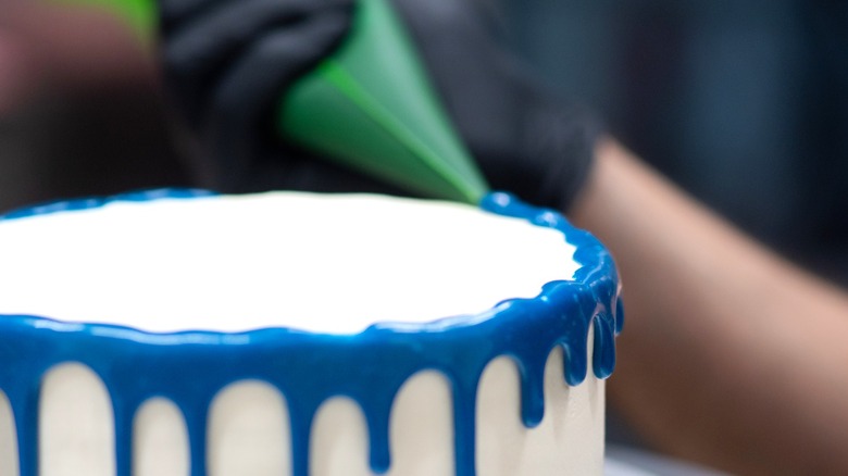 pastry chef applying vibrant drip frosting to a cake