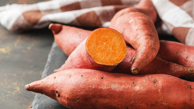 fresh sweet potatoes on a dark rustic background.