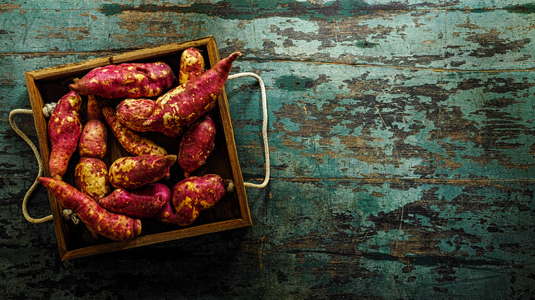 sweet potatoes in a crate on a wooden background