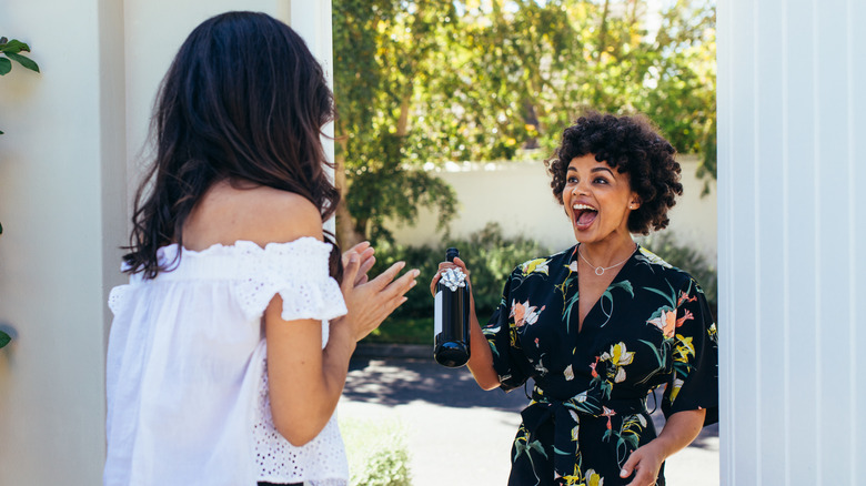 guest with bottle of wine at door