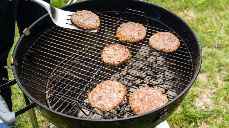 Hamburgers being cooked on charcoal grill with two zones
