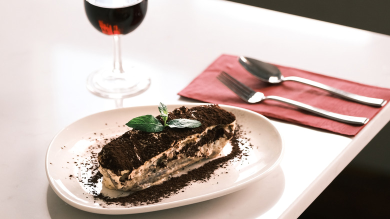 glass of red wine with tiramisu on white table