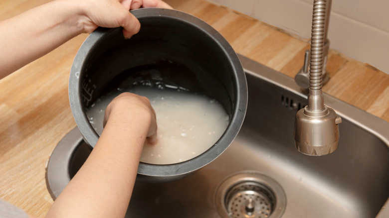 An individual washing rice in a cooker pot.