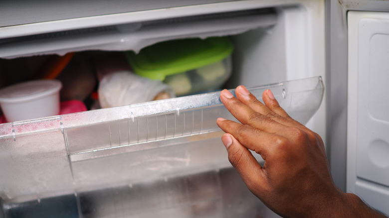 A person's hand is seen reaching into a home freezer.