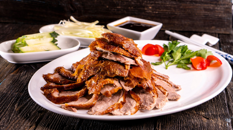 A pile of sliced Peking duck on a plate