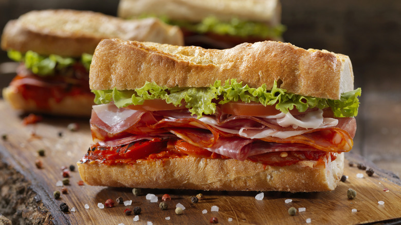 Italian sandwiches are arranged on a cutting board.