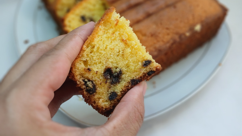 A hand holding a piece of sliced cake