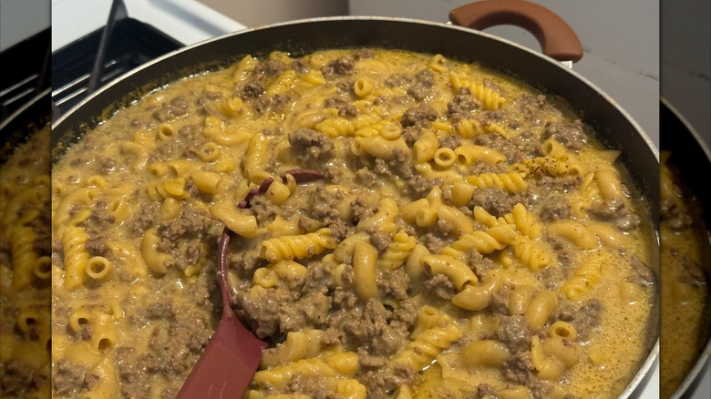 Pan of hamburger helper cooking on a stovetop.