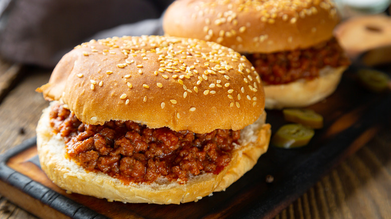 Two sloppy Joe sandwiches on a cutting board.