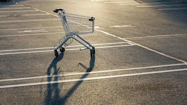 lonely looking grocery cart sitting in the middle of a parking lot