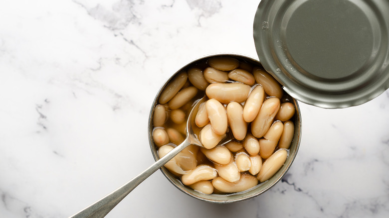 Top view of a spoon in a can of white beans.