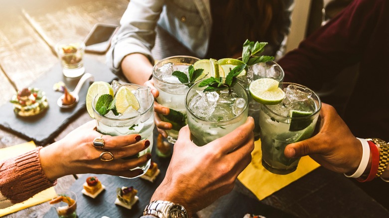 Friends cheers with colorful cocktails.