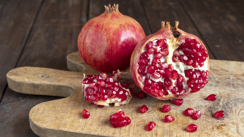 pomegranates sitting on a wooden cutting board