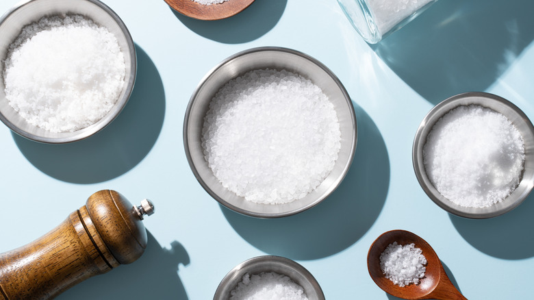 Bowls and spoons of salt photographed from above.