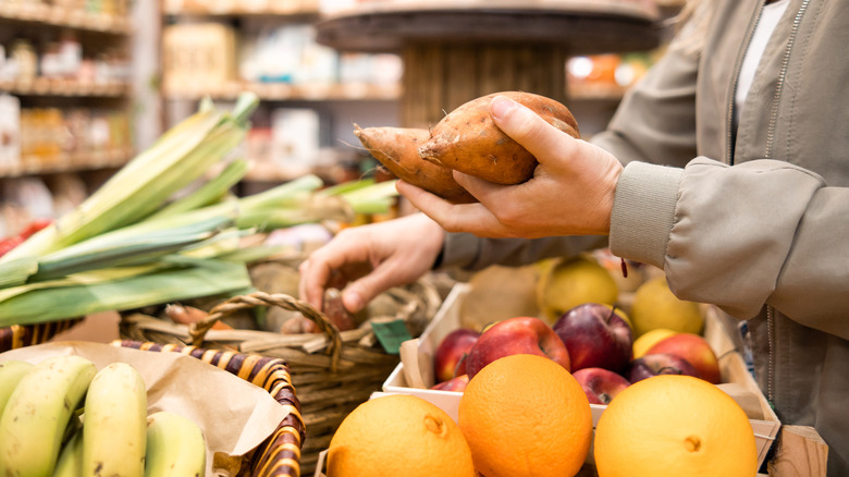 Hang holding sweet potatoes above grocery store produce baskets