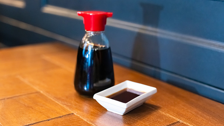 Soy sauce bottle, sauceboat bowl dish of soy sauce on wooden table, selective focus