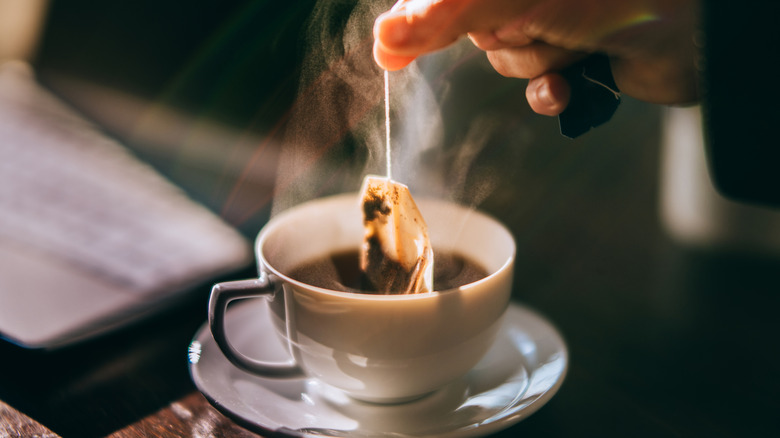 A tea bag being removed from a cup of tea