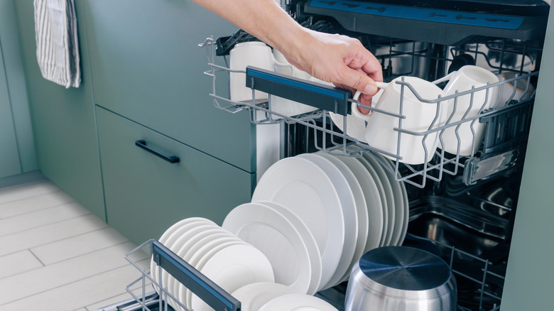 A hand unloading a dishwasher