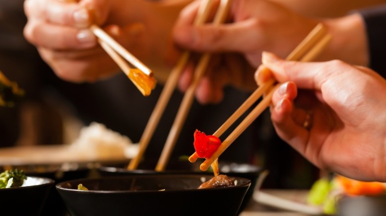 A group of people using chopsticks at a restaurant