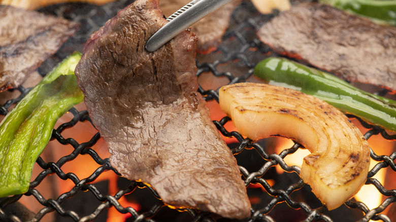 sliced beef and vegetables cooking on a hibachi grill