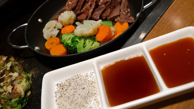 Hibachi steak and vegetables with a dish of sauces on the side