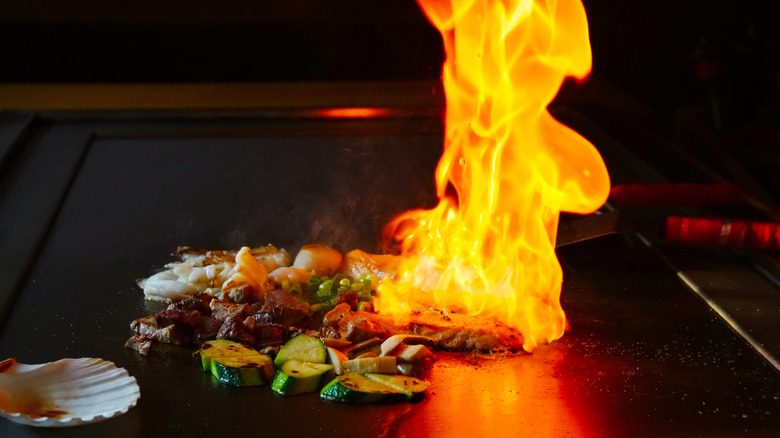 meat and vegetables with high flame on a teppanyaki grill top