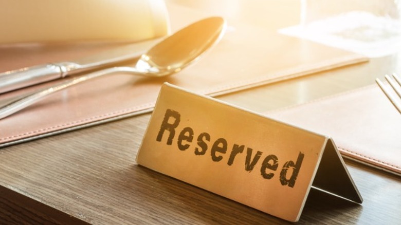 A reserved sign on a light wood table with napkins and flatware