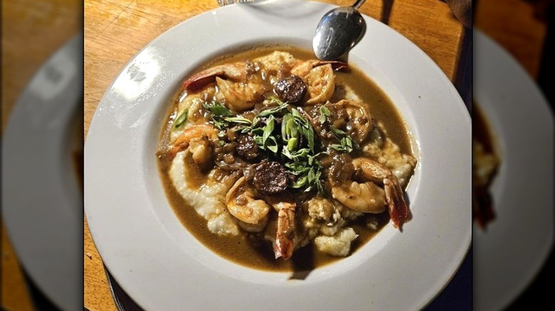 Shrimp piled on top of grits in a white dish with gravy
