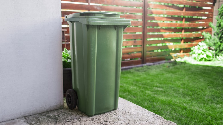 A large green outdoor trash bin.