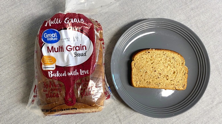 Bag of Great Value Multi Grain Bread beside a slice on gray plate