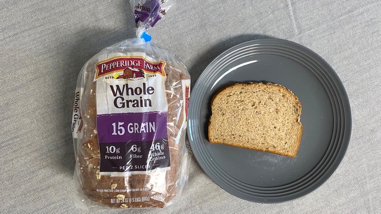 Bag of Pepperidge Farm Whole Grain 15 Grain beside a slice on gray plate