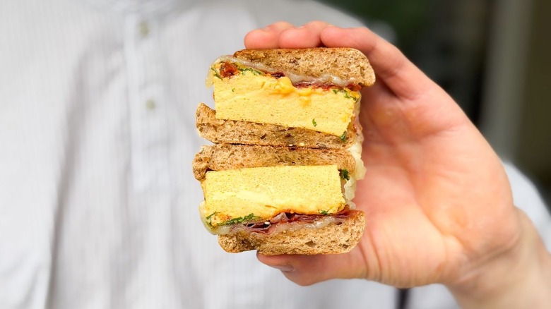 High-protein English muffin sandwich cut in halves and stacked in hand