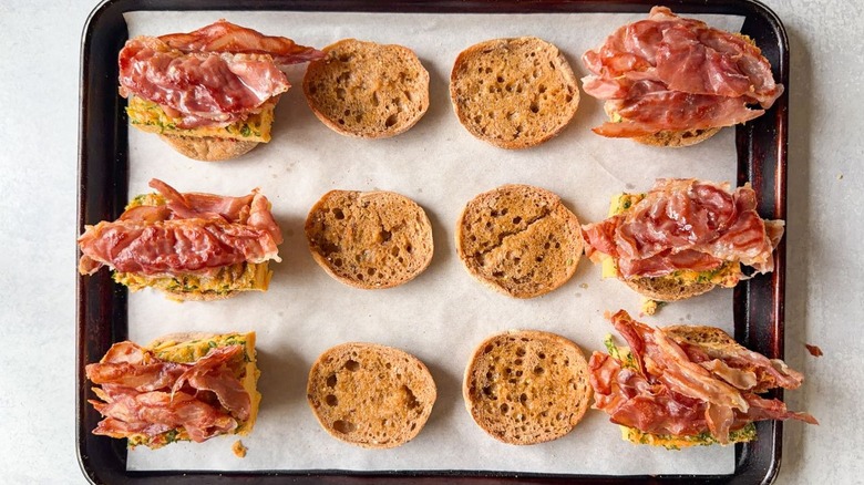 English muffin halves with baked eggs and prosciutto