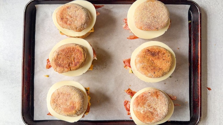 High-protein English muffin breakfast sandwiches ready to bake on parchment-lined baking sheet