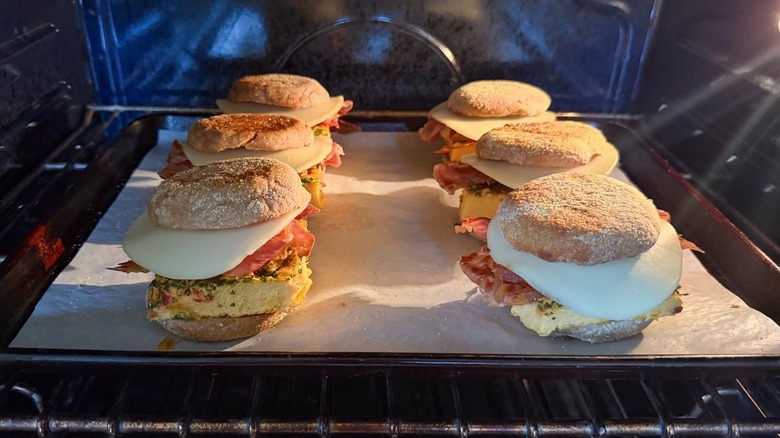 High-protein English muffin breakfast sandwiches on parchment-lined baking sheet in oven