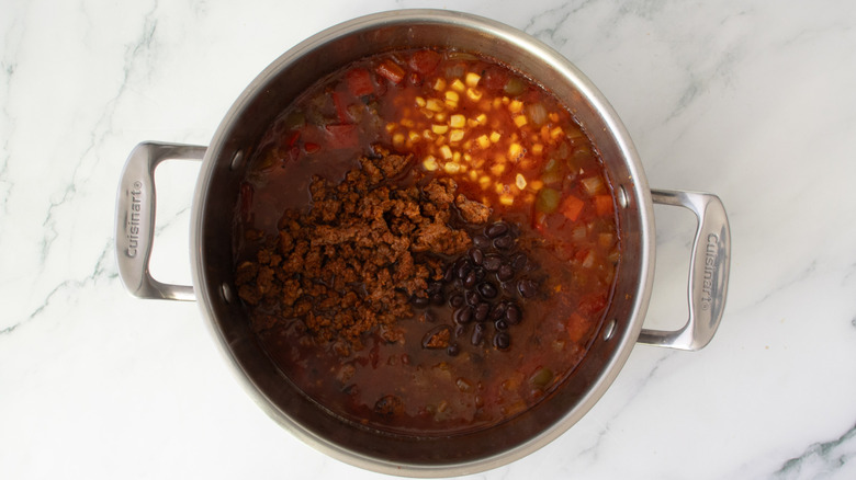 metal pot full of broth, ground meat, and vegetables