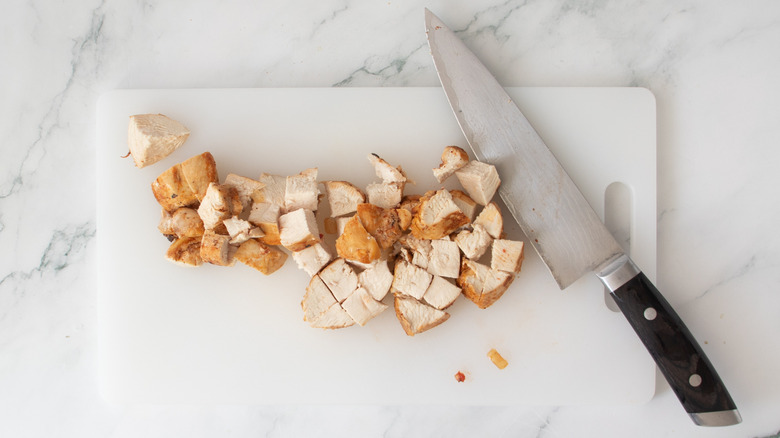 chopped chicken and a knife on a white board