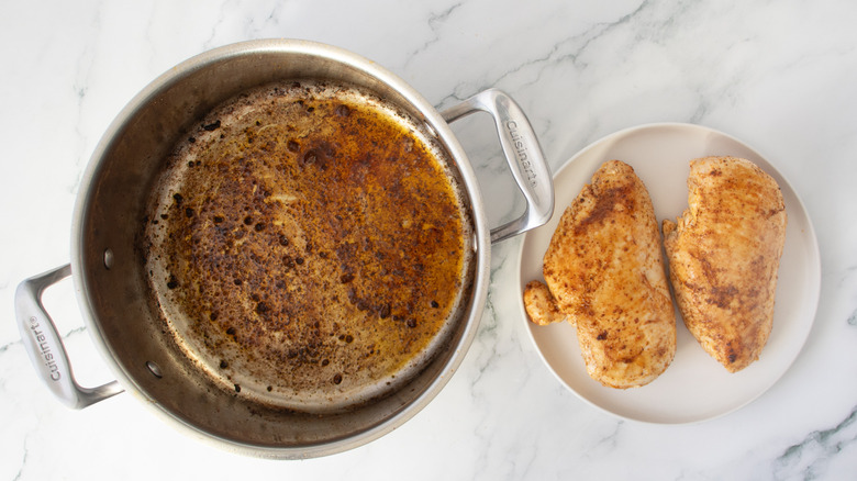 chicken breasts on a white plate next to a metal pot