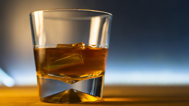 a close-up of bourbon in a glass with a blurry, gold and blue background