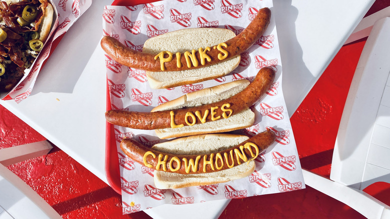 Pink's hot dogs with message written in mustard