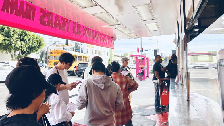 Customers read menus while waiting in line at Pink's Hot Dogs