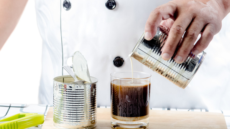 Hands pour sweetened condensed milk into coffee