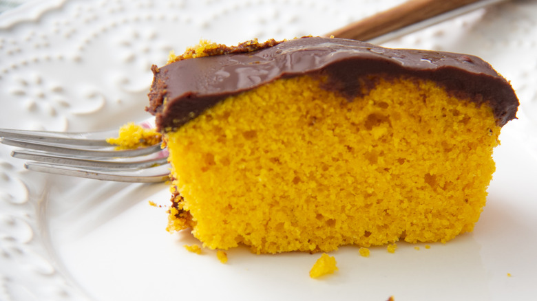 Yellow cake with chocolate icing on a white plate with fork