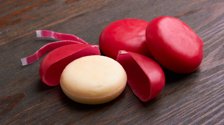 An unwrapped Babybel cheese on a wooden table.