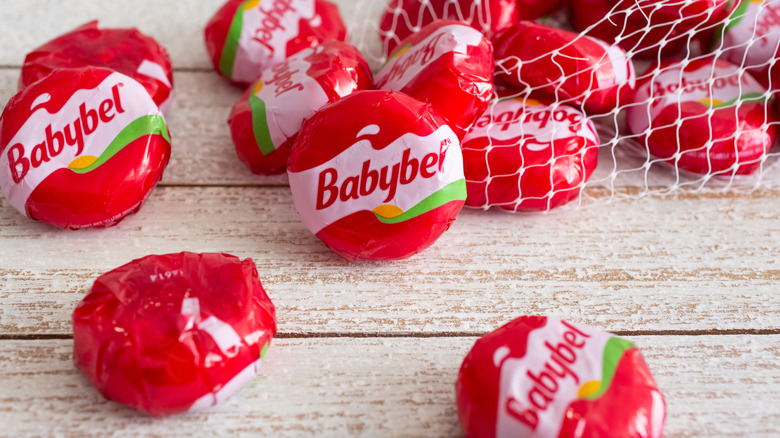 A package of Babybel cheeses on a wooden table.